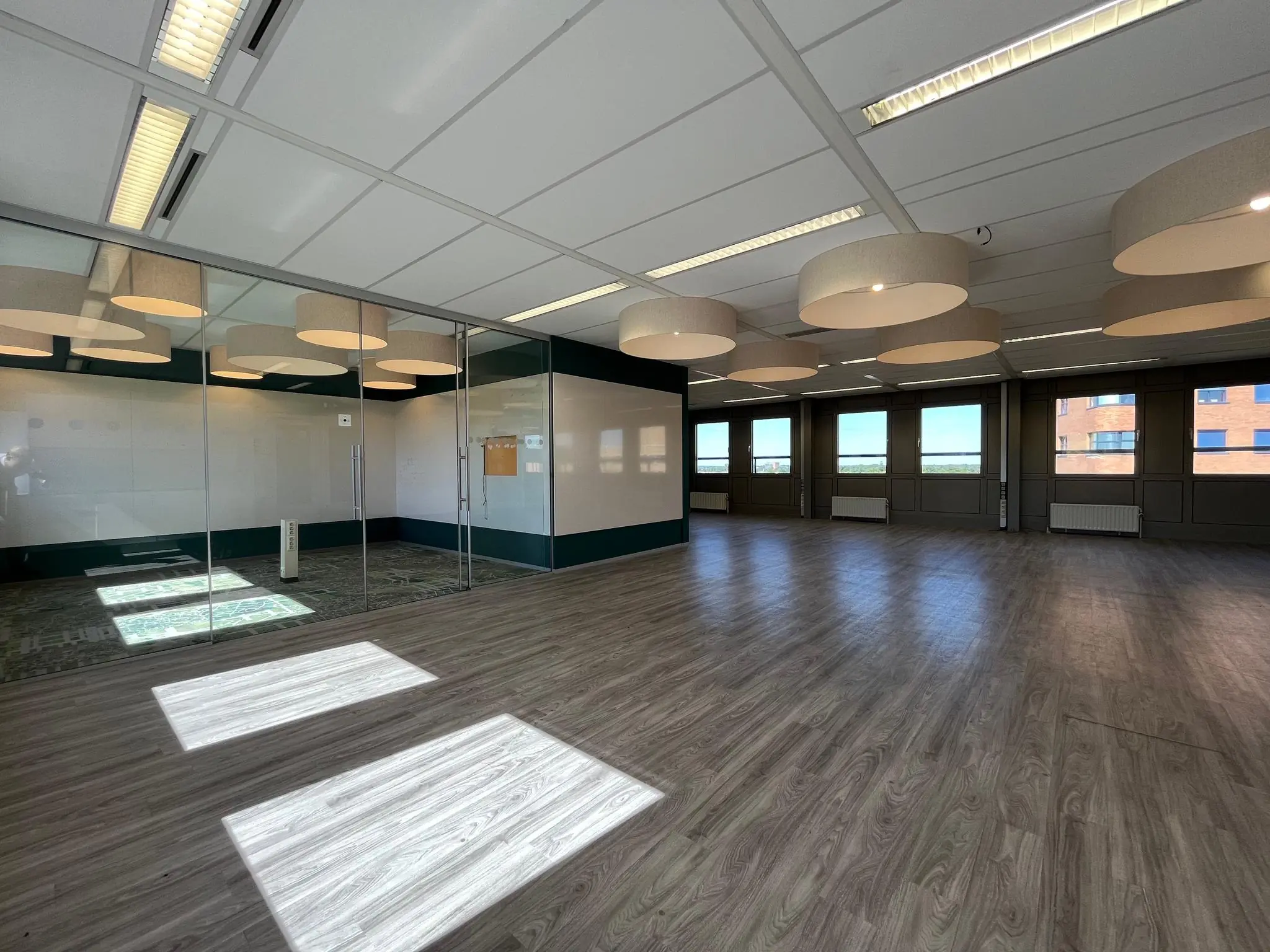 Lichte, moderne kantoorruimte aan de Barchman Wuytierslaan met glazen vergaderruimte en houten vloer.